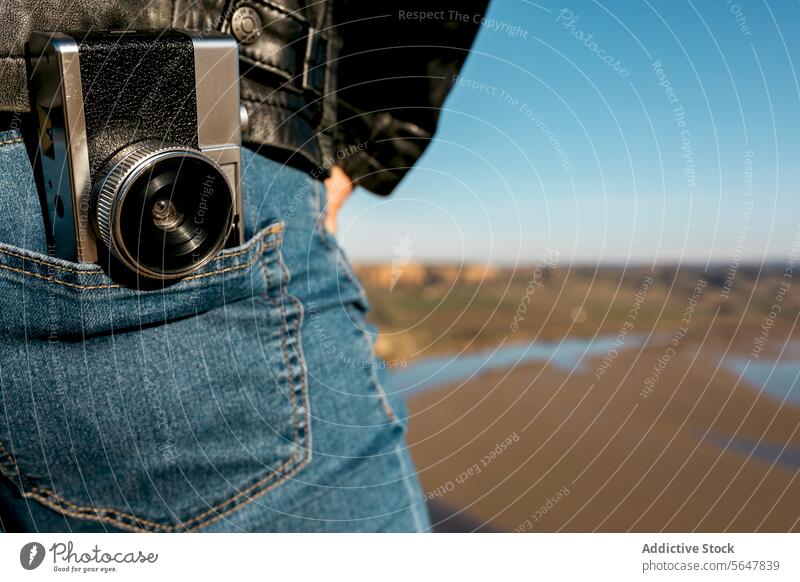 Detail view of a vintage camera tucked on traveler's jeans photography adventure river landscape outdoor nature close-up belt hip denim leisure hobby equipment