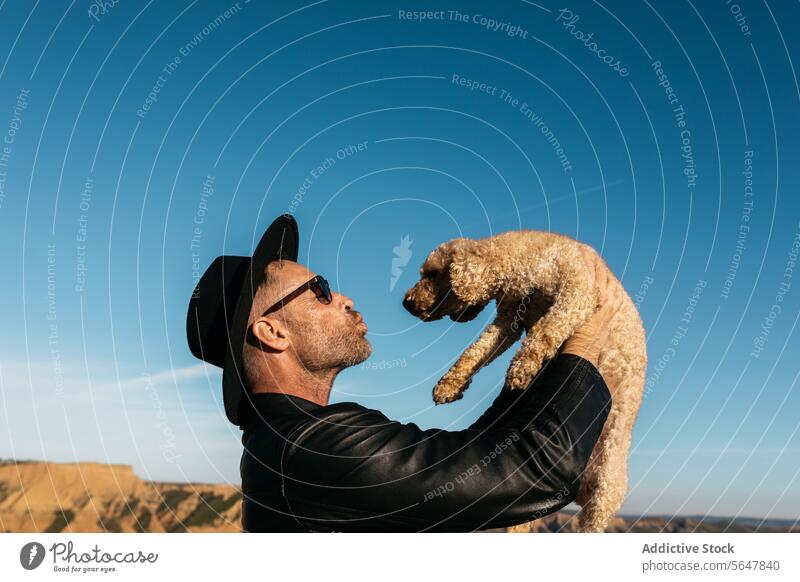 Joyful moment as man lifts dog against blue sky kiss joy lifting bond pet companion happiness outdoor leisure lifestyle friendship love casual day animal mammal