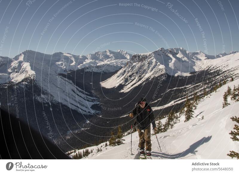 Person skiing on snowcapped mountain skier anonymous active pole backpack slope clear sky canada nature majestic beauty person unrecognizable landscape sunny