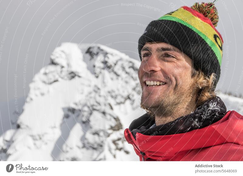 Active hiker in winter outfit against mountain peak traveler portrait warm clothes snowcapped clear sky vacation smile happy beard active standing person hiking