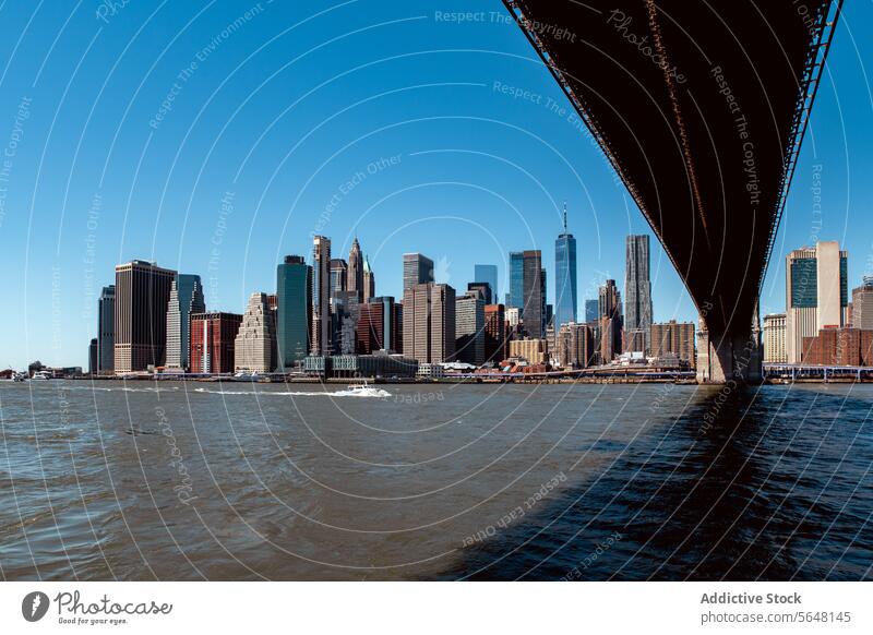 Underneath Manhattan Bridge Overlooking New York Skyline manhattan bridge skyscrapers blue river boat architecture buildings water skyline new york urban city