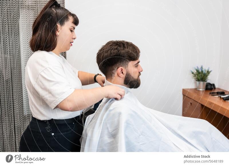 Side view of focused female hairstylist preparing to trim male client's hair at salon Hairdresser Man Salon Care Service Hand Client Process Hairstyle Job