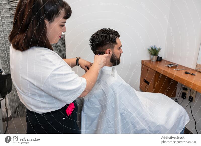 Side view of focused female hairstylist using electric trimmer on male client's hair at salon Hairdresser Trimmer Man Salon Care Service Hand Client Process