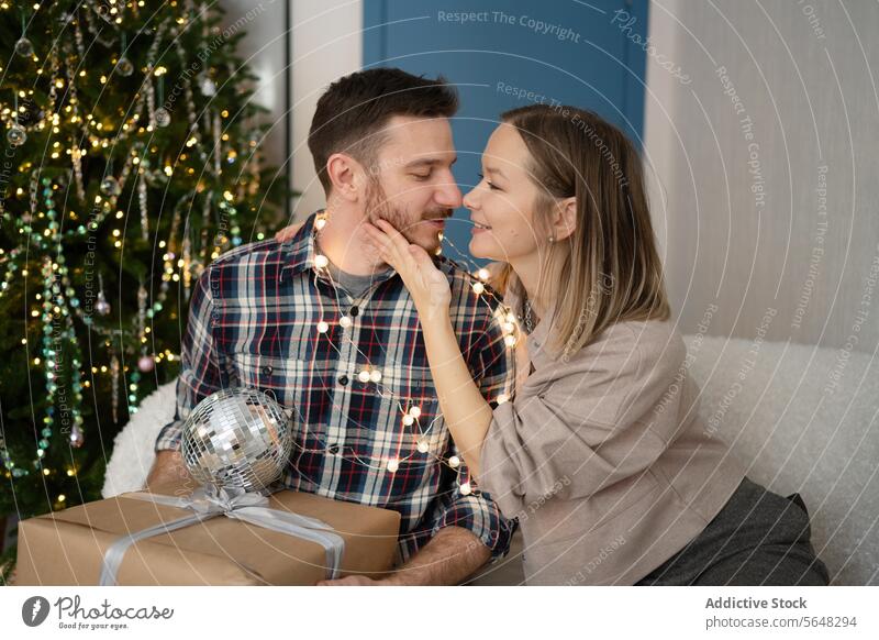 Happy Couple exchanging affectionate gestures near Christmas tree at home couple gifts holiday season joy intimacy decoration festive celebration love sharing