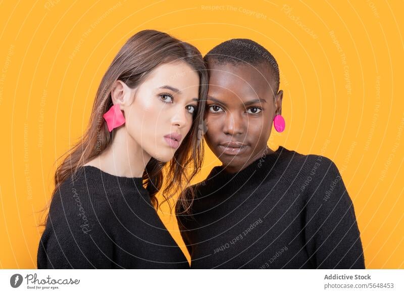 Diverse young female friends wearing pink earrings women diverse confident portrait trendy tshirt together multiracial casual attire posing pierced staring