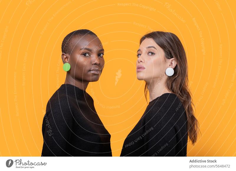 Diverse young female friends wearing pink earrings women diverse confident portrait trendy tshirt together multiracial casual attire posing pierced staring