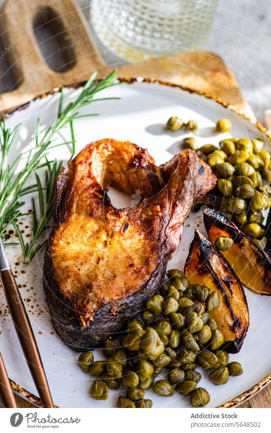 Close-up of a barbecued salmon steak seasoned with spices served with roasted lemon slices and capers garnished with rosemary Barbecue spiced close-up healthy