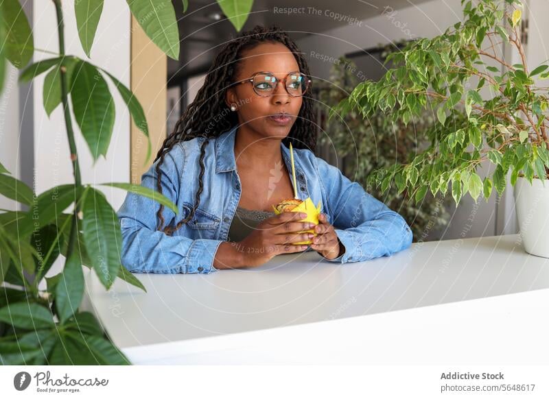 Businesswoman blowing candle on cupcake in creative office Cupcake Candle Blow Thoughtful Creative Office Afro Young Birthday Celebrate Food Looking Away