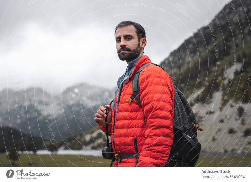 Adult man in orange winter jacket hiking in mountains Man Hike Tourist Portrait Confident Mountain Winter Jacket National Park Backpacker Traveler Nature