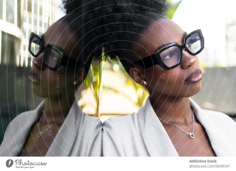 Pensive black female manager wearing eyeglasses leaning on glass wall businesswoman contemplate reflection beautiful pensive headshot fashionable hair curly