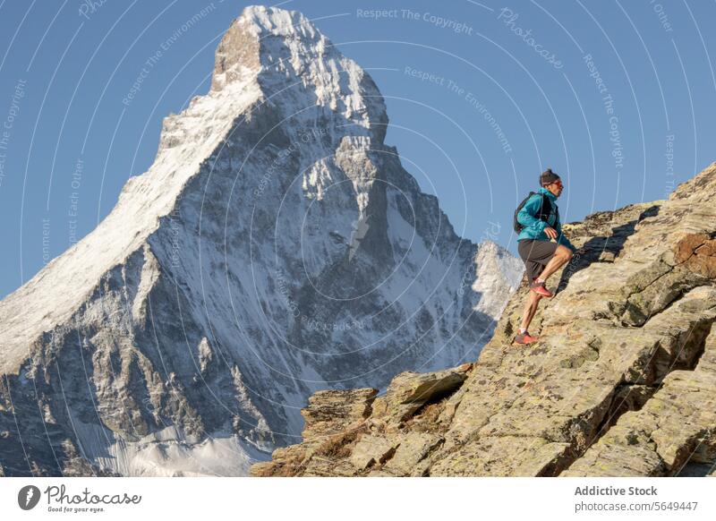 Hiker with his back to the Matterhorn hiker trail mountain rocky athletic gear navigation iconic background outdoor adventure alpine peak summit snow landscape