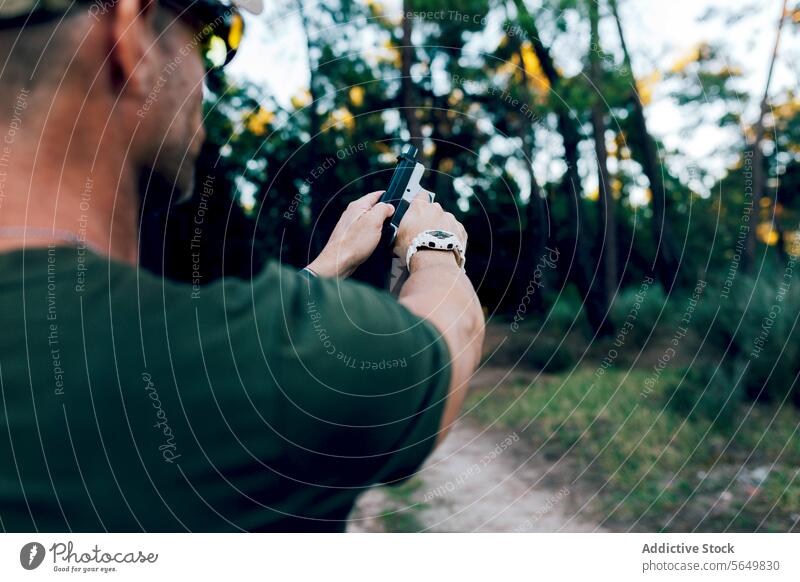 Back view of Anonymous military soldier holding weapon against forest man commando handgun practicing shooting anonymous training target unrecognizable army