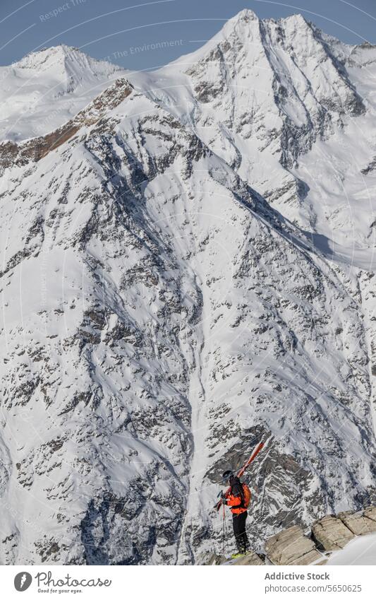 Full body of unrecognizable backpacker in warm clothes standing on rock against snowy mountains during vacation in Zermatt Tourist Ski Backpack Snow Mountain