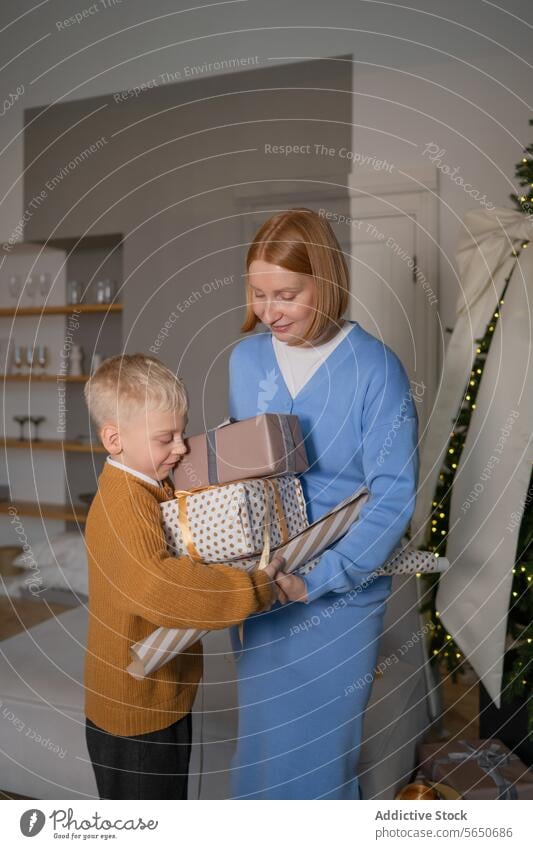 Joyful mother and son sharing Christmas presents christmas gift joy holiday cozy decoration festive boy smile adoring room family celebration giving bonding