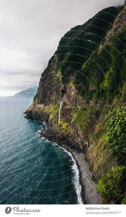 Idyllic coastal landscape with waterfall mountain sea coastline cliff beautiful scenery rock green sky cloud idyllic plant shore beach nature scenic travel view