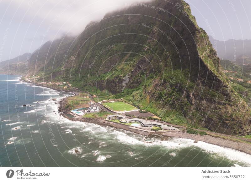 Aerial view of sea and mountain range coastline beach resort luxury hotel rocky wave foothill green architecture landscape nature travel residential scenic