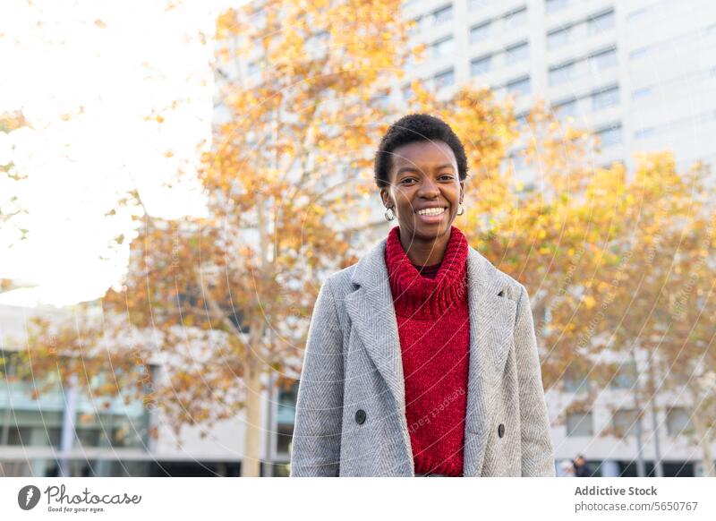 Confident happy African American businesswoman standing against urban buildings downtown skyscraper city self assured weekend outerwear confident serious