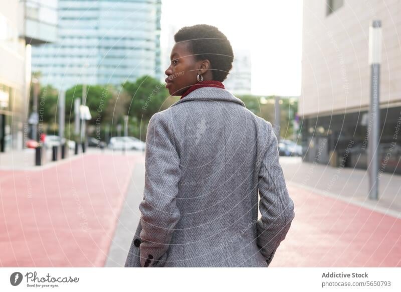 Black businesswoman walking with hands in pockets hand in pocket city street downtown building urban charismatic respectable serious confident self assured