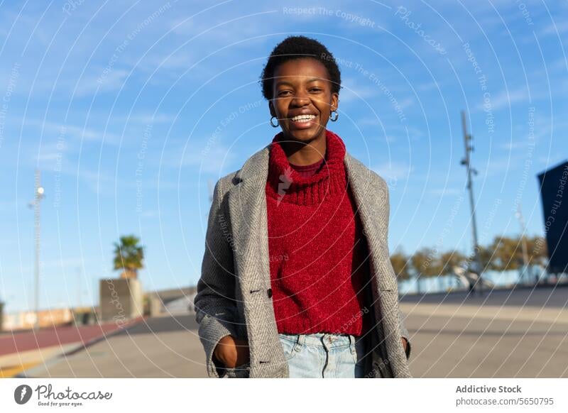 Cheerful black woman strolling in city hand in pocket walk weekend free time town urban sunlight smile cheerful happy female adult african american ethnic afro