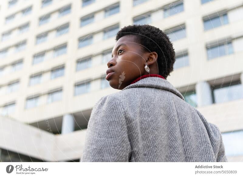 From below black woman standing street against building in town lady pleasure modern outfit style urban casual young female confident businesswoman jacket