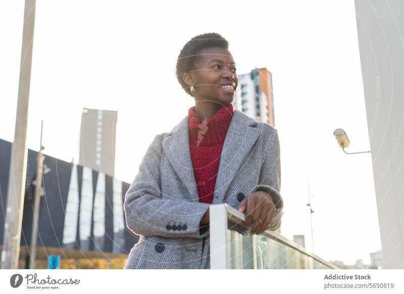 Smiling black woman standing in city during day off lean on railing weekend free time town urban district outerwear smile cheerful happy female adult