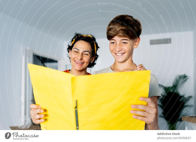 Mother and son having fun while studying documents on yellow file mother examine enjoy time together woman boy relocate apartment love home check parent casual