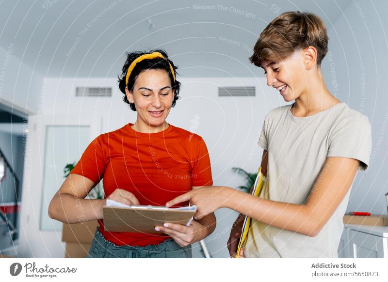 Mother and son checking notes on clipboard together and smiling mother discuss read detail smile woman cheerful happy cooperate teamwork take note conversation