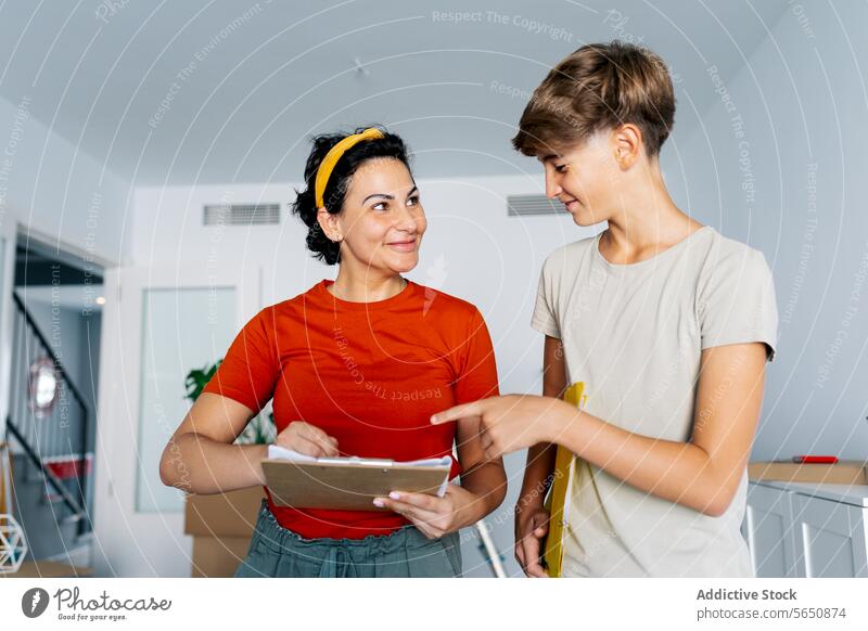 Mother and son checking notes on clipboard together and smiling mother discuss read detail smile woman cheerful happy cooperate teamwork take note conversation