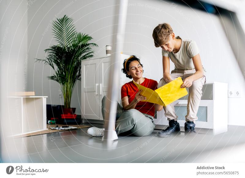 Mother and son sitting and reading notes on file mother study relocate new apartment woman notebook mom together boy positive happy casual parent home learn