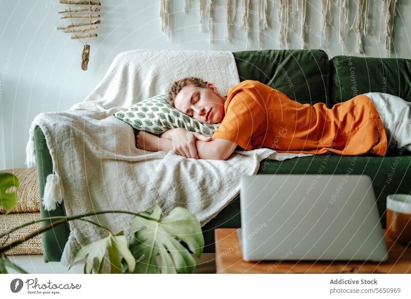 Young woman sleeping on comfortable sofa with cushion at home near laptop and mug apartment couch relax asleep nap connection internet freelance pillow flat