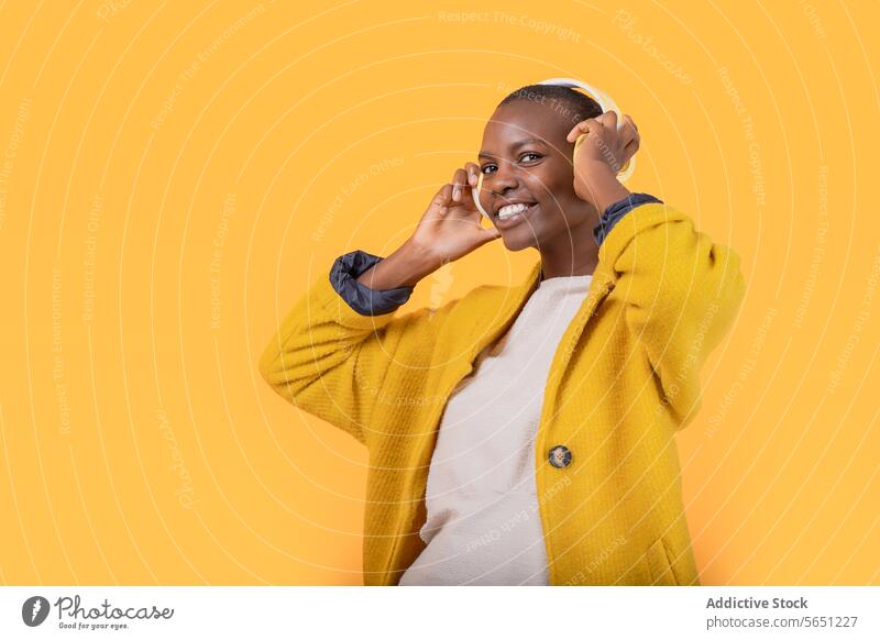 Happy black young woman enjoying music through wireless headphones cheerful listening ethnic african american happy smile casual attire lifestyle cool device