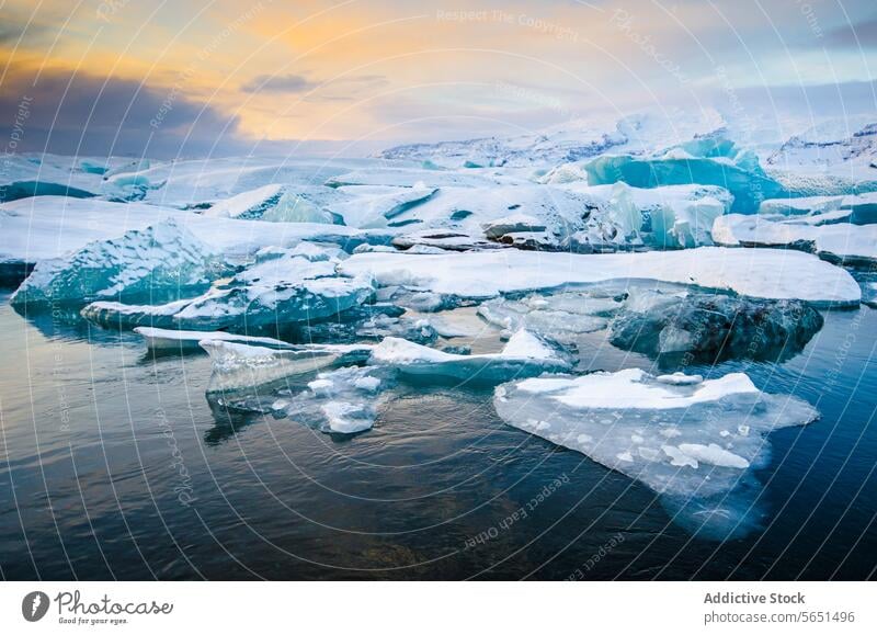 Glacial icebergs floating in a lagoon with a backdrop of a snowy mountain landscape during sunset in Iceland glacier water cold nature scenic arctic frozen