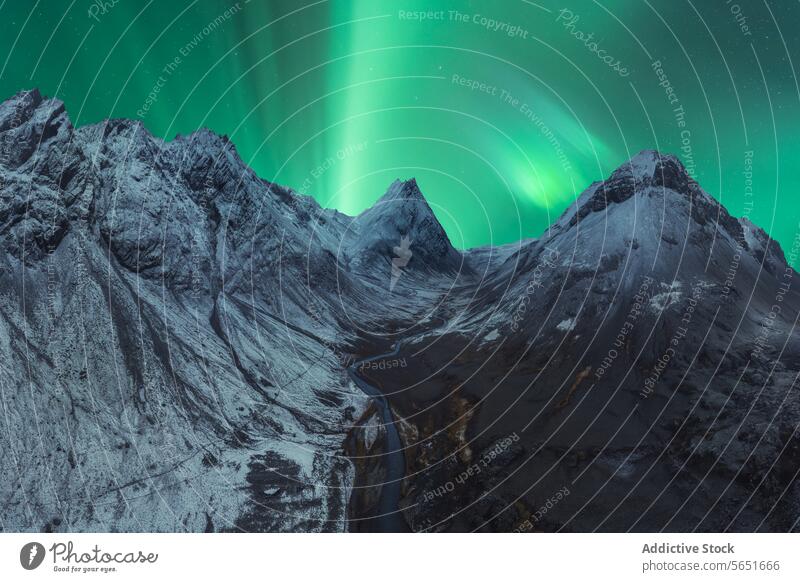 Sharp mountain peaks under a vibrant Northern Lights display in Iceland aurora borealis northern lights river snow winter night sky stream green natural wonder