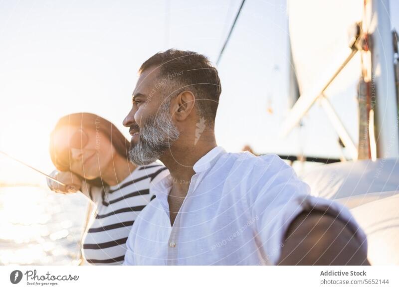 Smiling couple sitting on yacht smile pleasure enjoy relax sea happy trip romantic peaceful lifestyle casual adventure paradise embrace hug sailboat tourism