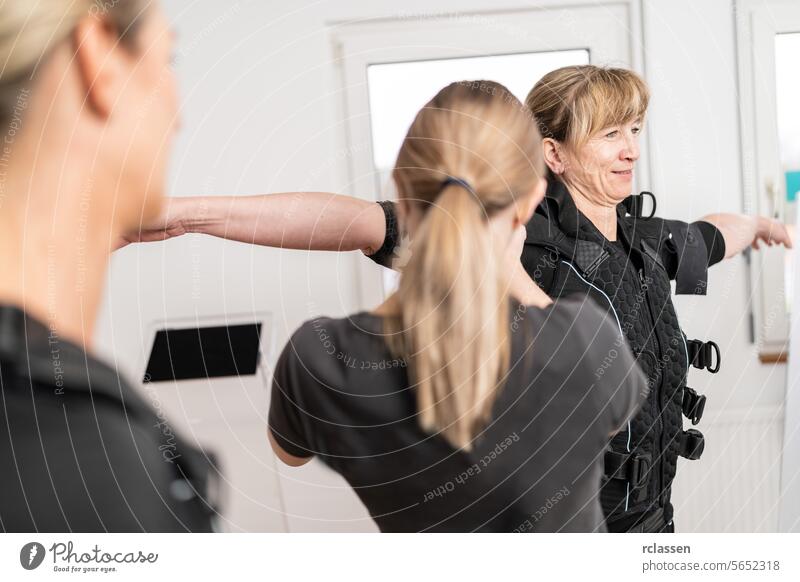 Trainer fitting an EMS training suit on a client in a EMS Studio environment. electro stimulation neuromuscular electrical endurance body sculpting gym session