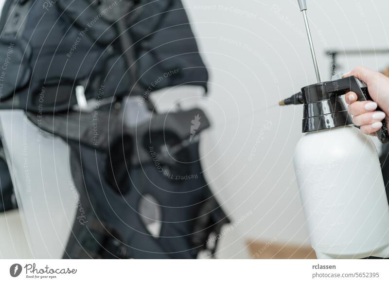 Close-up of a hand operating with a spray bottle to preparing ems vest in a EMS - Studio instructor ems suit close-up maintenance equipment care gym gear