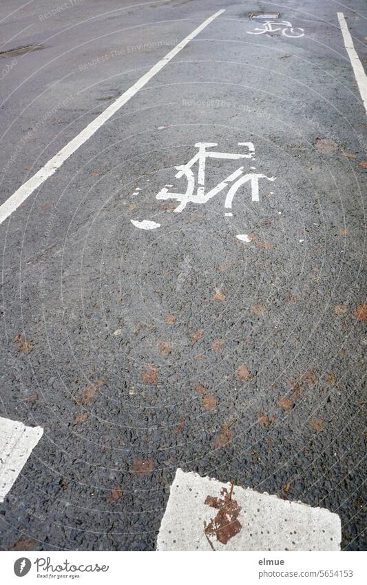 Marked cycle path on gray asphalt with two slowly dissolving bicycle pictograms ride a bicycle Bicycle Asphalt road Lane markings Pictogram Cycle path Blog StVO