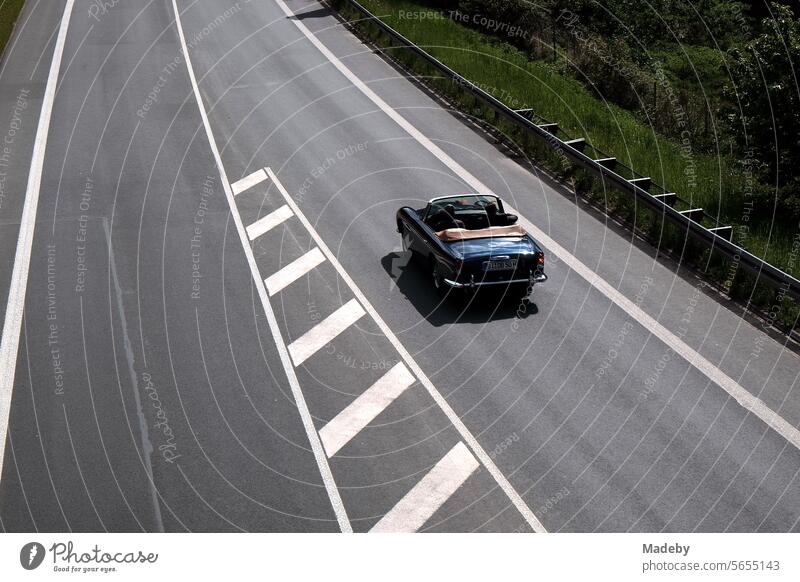 Sinfully expensive rare British sports car classic of the sixties in summer sunshine on the tunnel road in Oerlinghausen near Bielefeld on the Hermannsweg to the Teutoburg Forest in East Westphalia-Lippe