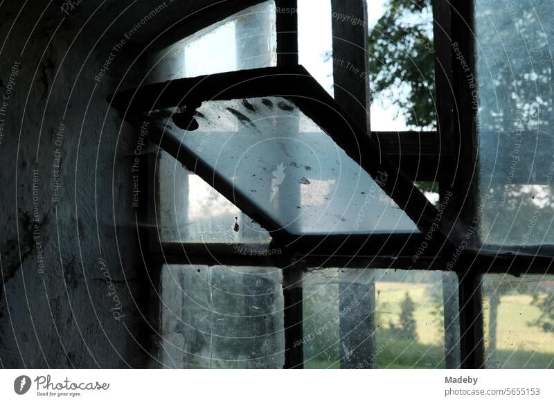 Old tilted window of a former cowshed in summer on an old farm in Rudersau near Rottenbuch in the Pfaffenwinkel district of Weilheim-Schongau in Upper Bavaria