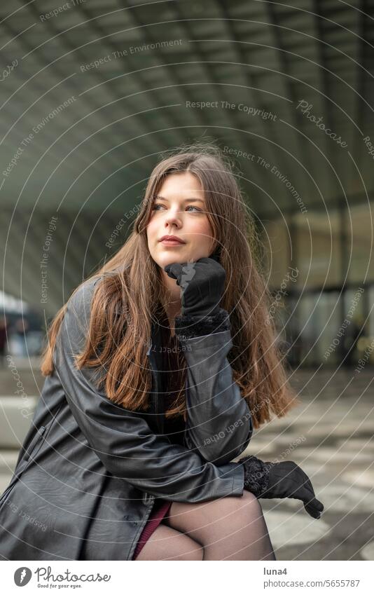 Self-confident young woman with a black coat Woman Meditative sensual Dreamily self-aware Elegant emancipated urban fortunate youthful fashion Longing Smiling