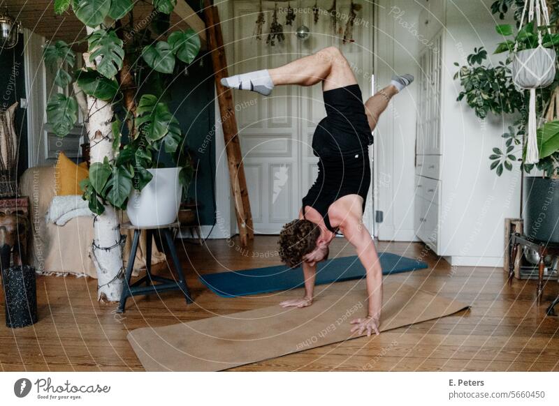 Young man doing a handstand in a beautiful living room on a yoga mat personal trainer Living room Fitness mat Workout workout Yoga Healthy Cozy home workout