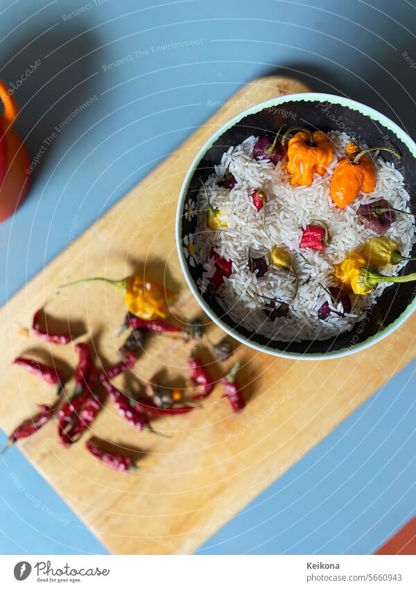 Hot, colorful chilies in the rice and on the wooden plate. Chili Chili peppers Rice variegated Wooden board Peperonis tart Tangy Blue Orange Red