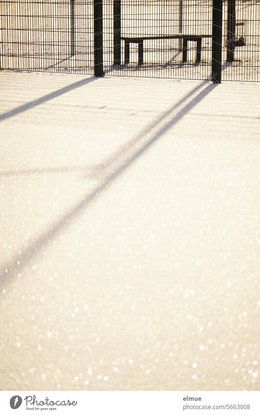 Snow-covered sports field with bench, fenced in with a ball fence Sports fence Bench Sporting grounds Ball sports snow-covered Winter Ball catching grid