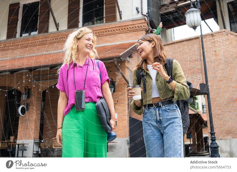 Cheerful multiethnic women walking outdoors, with one holding a coffee cup, in a relaxed, post-work setting in Chiang Mai, Thailand smiling cheerful smile Asian