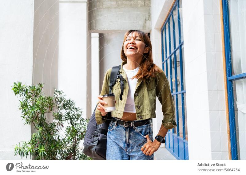 Cheerful Asian woman with a backpack and coffee cup, walking outdoors, showcasing the flexible life of remote working in Chiang Mai, Thailand joyful cheerful