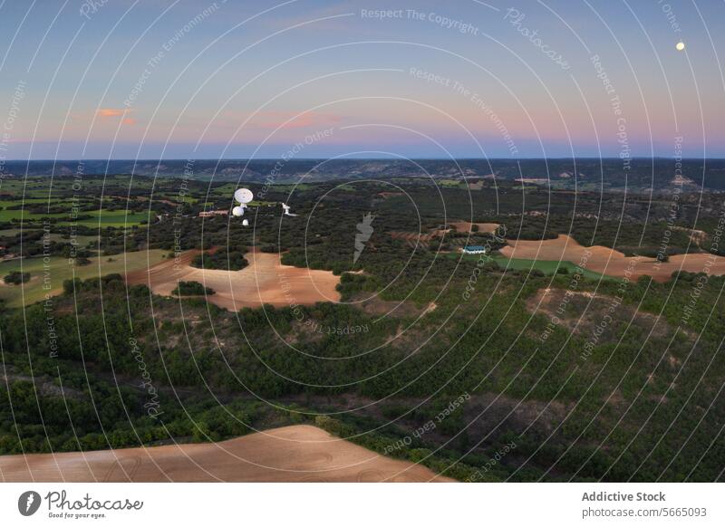 Twilight descends over Alcarria with satellite dishes nestled among the rolling hills and a moonlit sky Aerial Guadalajara twilight landscape bird's eye nature