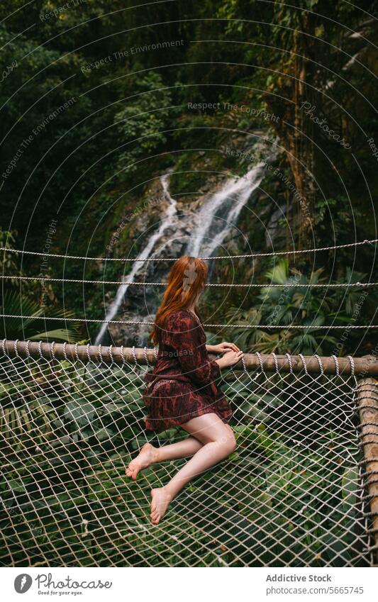 Woman on Suspension Bridge in Jungle Waterfall Setting in Minca, Colombia woman dress sitting net suspension bridge jungle waterfall background natural scenery