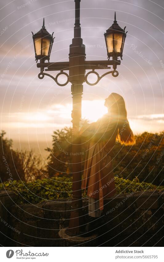 Serene sunset moment with woman and street lamp in Bogotá, Colombia tranquil serene glow old-fashioned standing soft light dusk evening peaceful silhouette