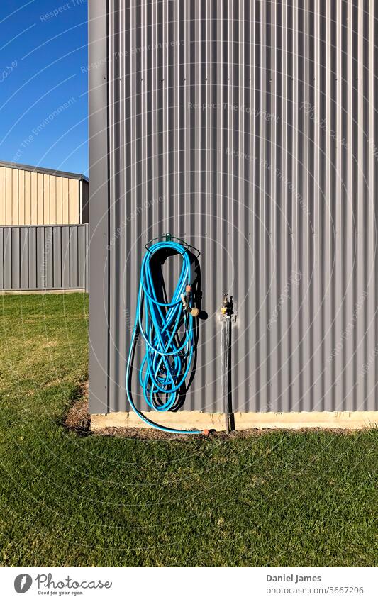 Suburban minimalism with hose, sheds and yard on a sunny day. Grass Hose Sky Minimal Minimalistic minimalist Square buildings Structures and shapes Sparse