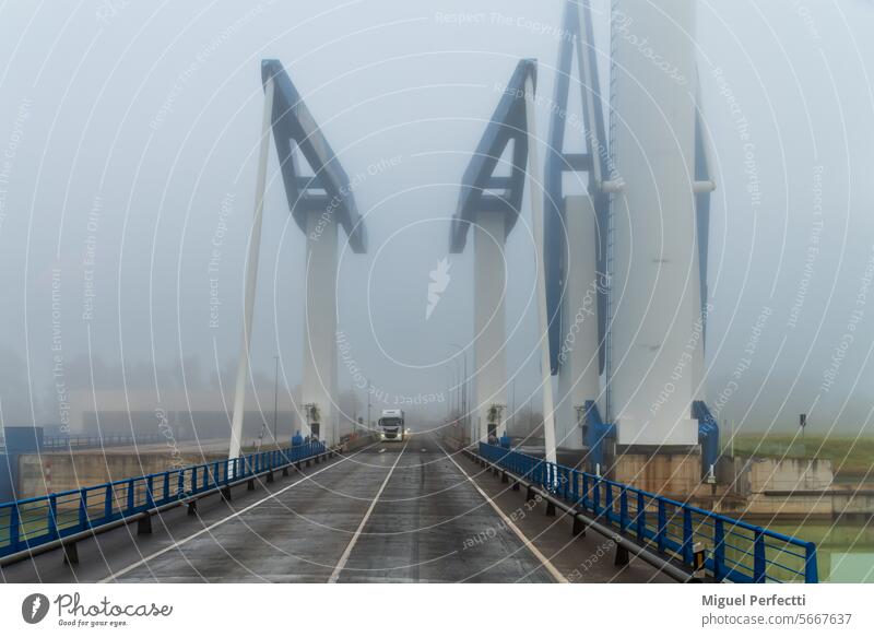 Truck driving on the drawbridge of the Seville lock on a foggy day. truck road river counterweight circulation transport traffic trailer engineering gate canal